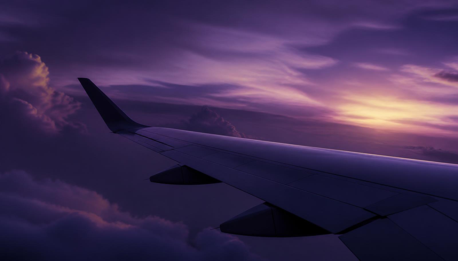 Asa de avião comercial sobre nuvens ao anoitecer